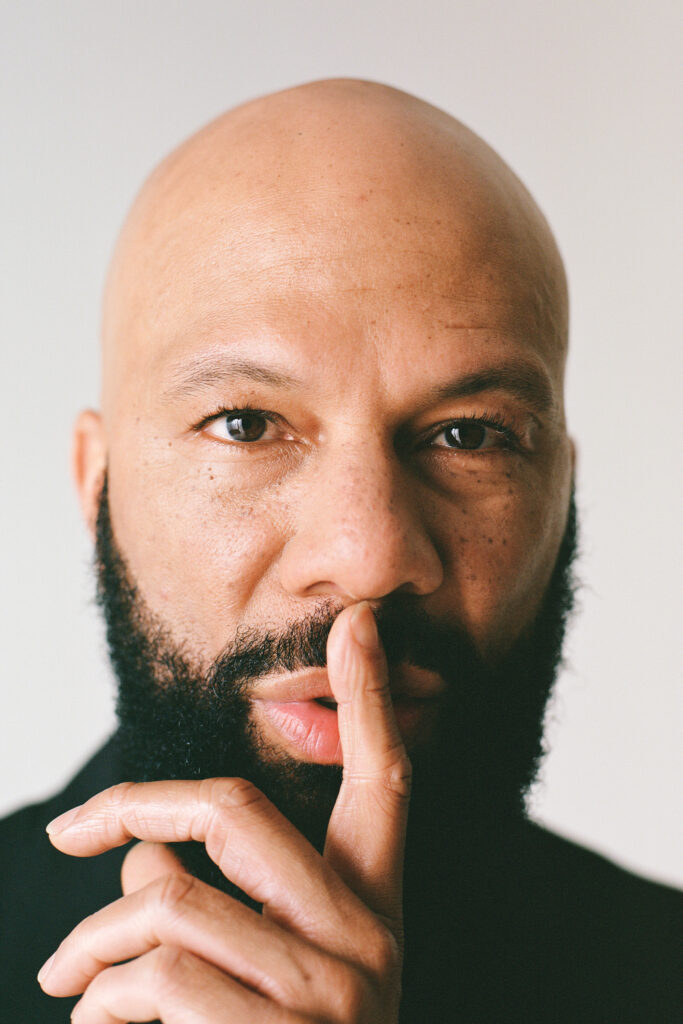 Common holds a finger over his mouth in close-up headshot