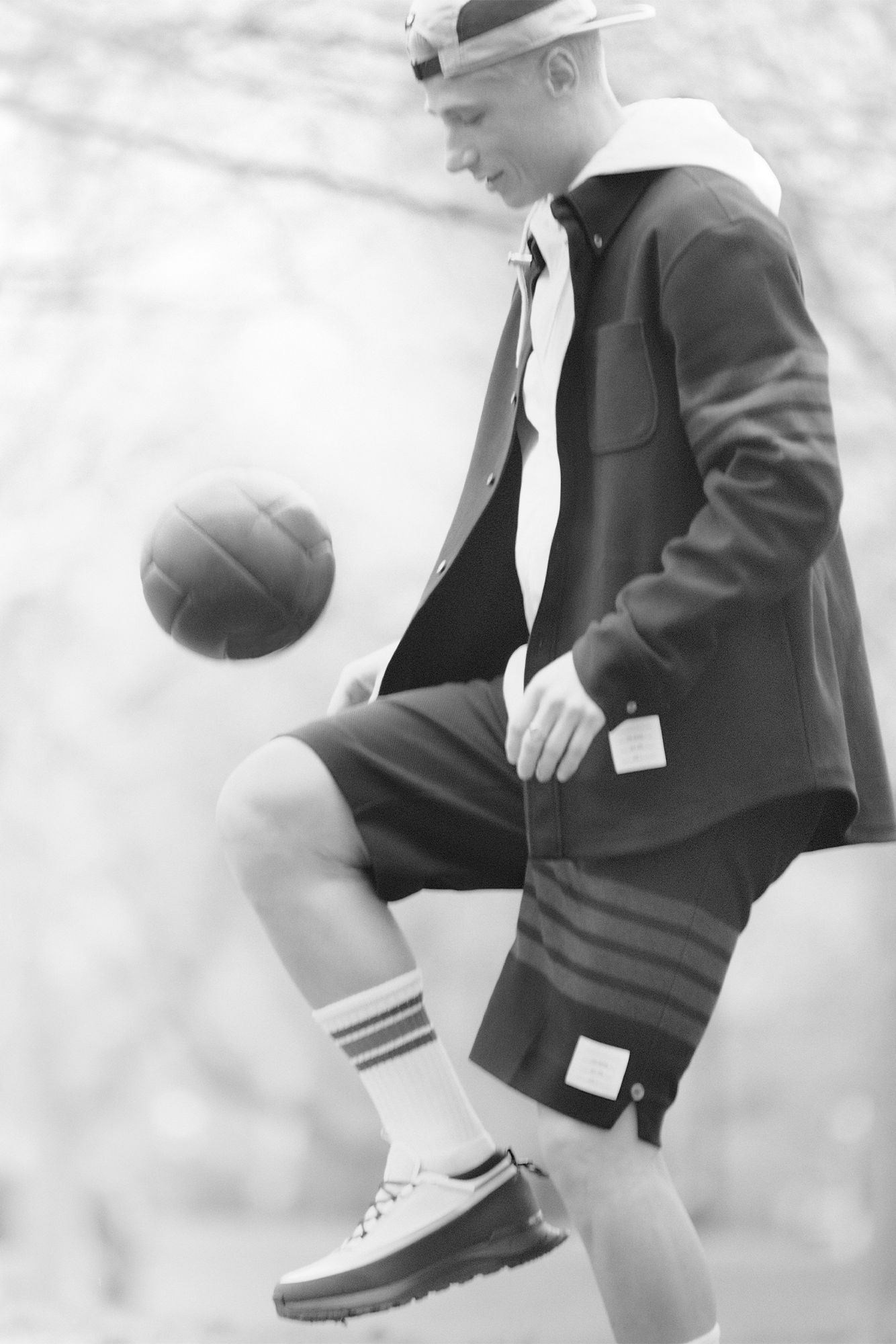 Male model in black and white in suit jacket, button down and shorts bouncing ball